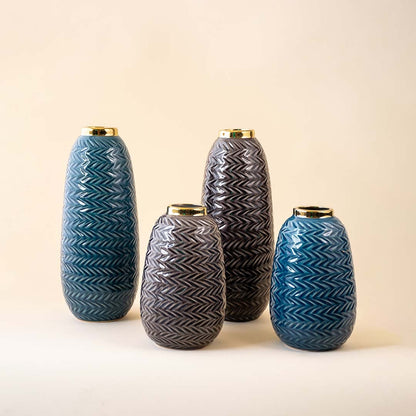 Collection of blue zigzag ceramic vases with gold detailing arranged elegantly on a marble surface in a modern classic room.