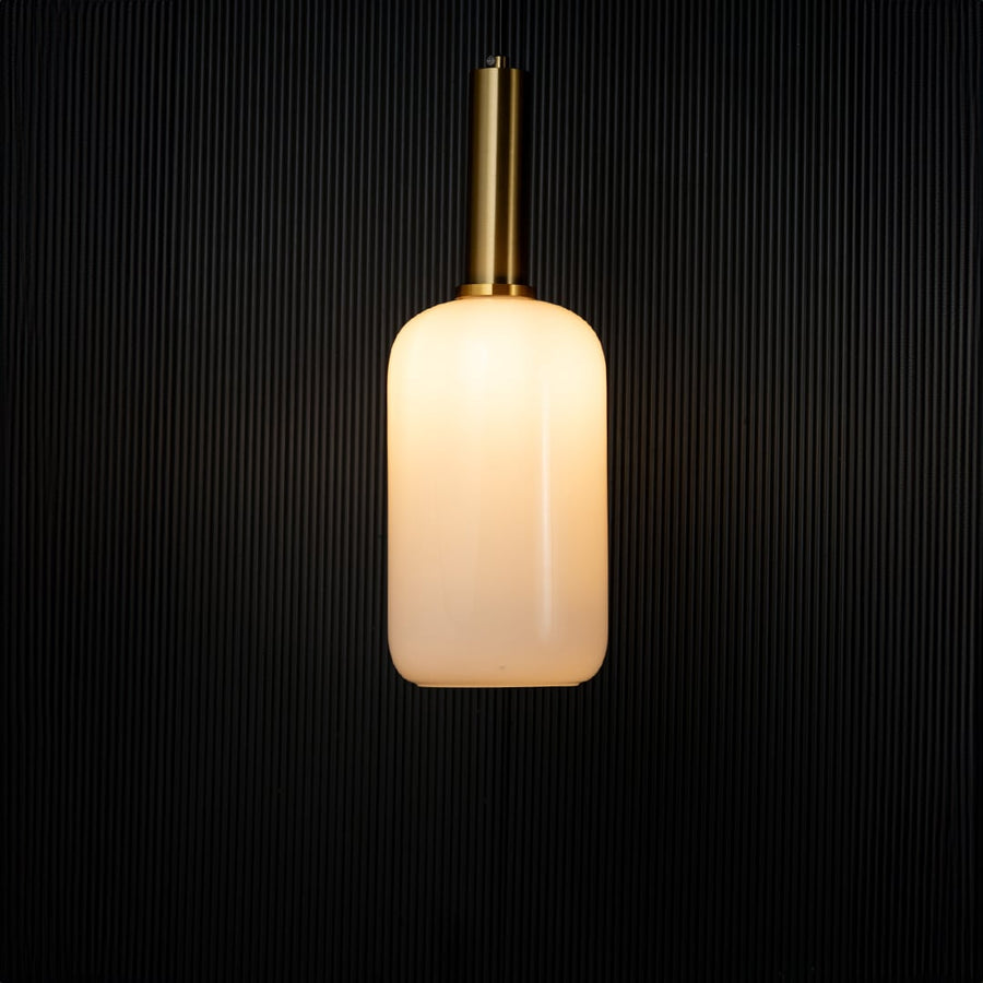 Elegant white glass pendant light turned on with golden holder glowing warmly against black background decor.