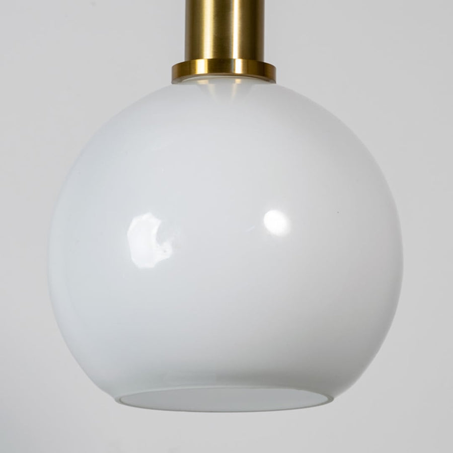 White glass globe pendant light with brass metal holder showcasing smooth glossy finish and modern lighting elegance.