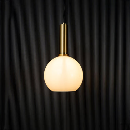 Stylish globe pendant light turned on with warm glow creating modern ceiling decor effect on black background.