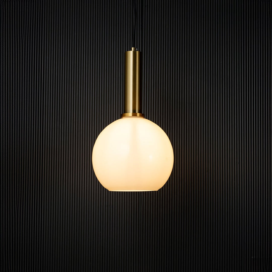 Stylish globe pendant light turned on with warm glow creating modern ceiling decor effect on black background.
