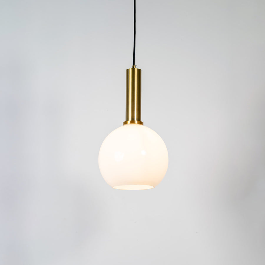 White glass globe pendant light with brass metal holder and minimalist design for contemporary ceiling lighting decor.