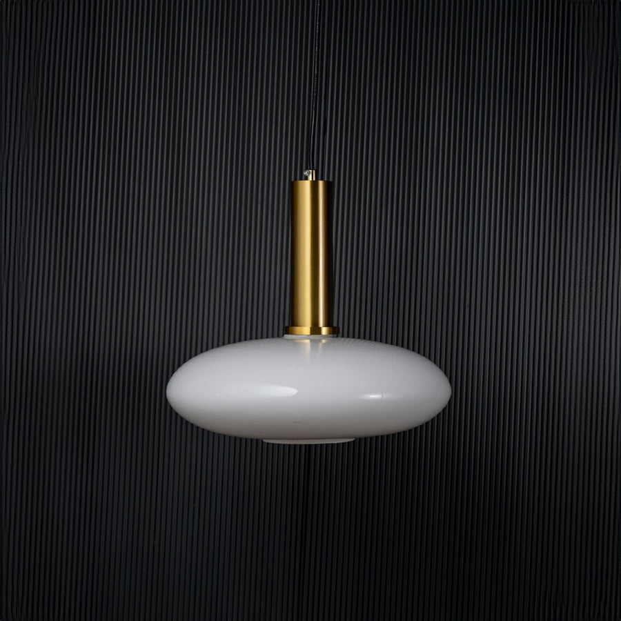 Disc pendant light turned off with brass accent and glass shade displayed as modern ceiling decor on black background.