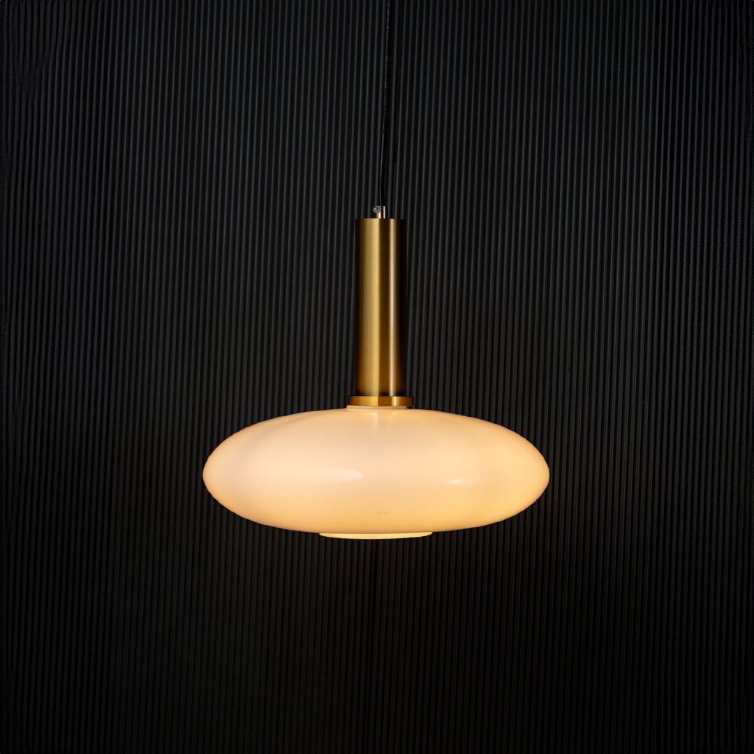 Elegant disc pendant light turned on with warm glow creating ambient ceiling decor on black background.