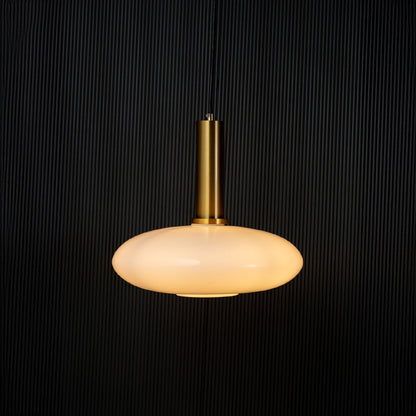 Elegant disc pendant light turned on with warm glow creating ambient ceiling decor on black background.
