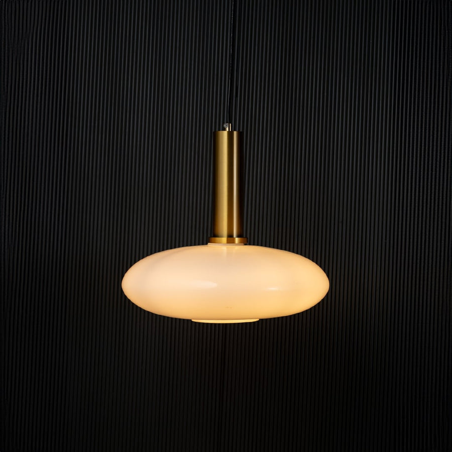 Elegant disc pendant light turned on with warm glow creating ambient ceiling decor on black background.