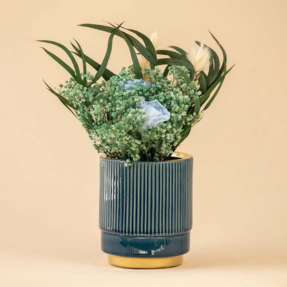 Blue ribbed ceramic vase with gold rim displayed in a soft neutral room highlighting its textured design and elegant contemporary styling.