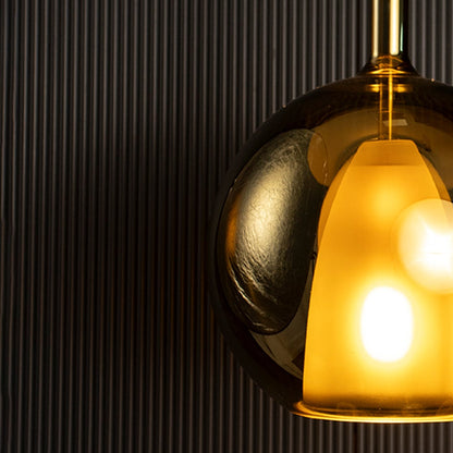 Closeup of amber pendant light showing clear round glass shade with soft diffused inner light for gentle glow.