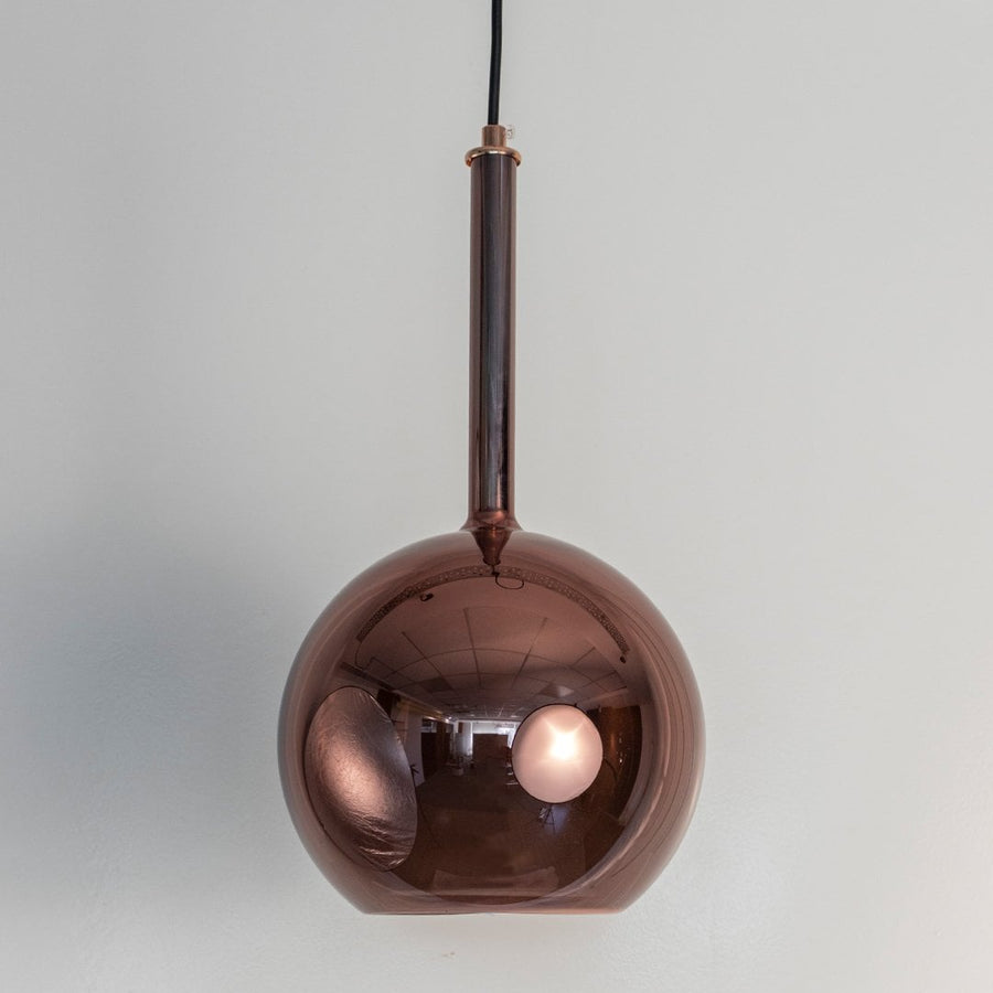 Amber pendant light off white background showcasing elegant glass shade and sleek black suspension cord.