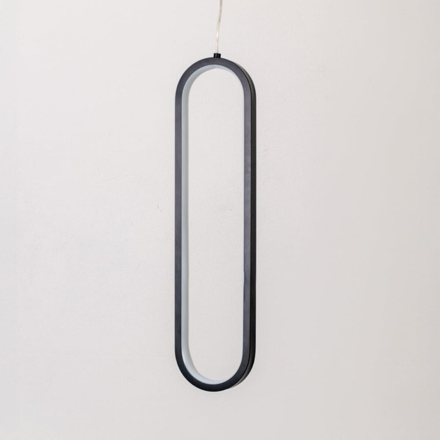 Modern metal elongated loop hanging light in black and white shown switched off on white background for minimal wall decor.