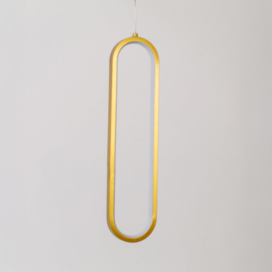 Modern metal elongated loop hanging light in gold shown switched off on white background for minimal wall decor.