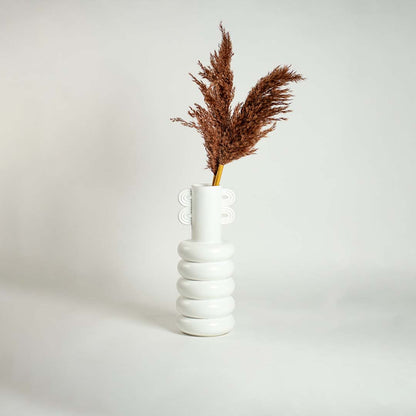 White ceramic sculpted vase with loop handle styled in a modern home setting adding elegant artistic decor to shelves and tabletops.