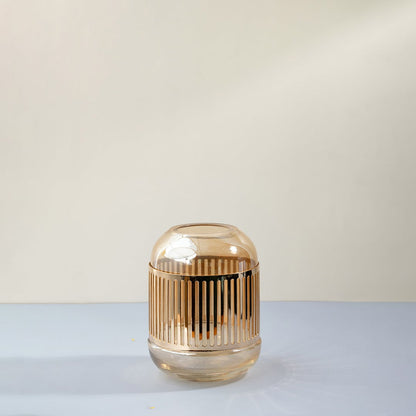 Decorative glass candle holder with vertical ribbed design and warm amber finish displayed on white background for modern table decor.