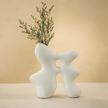 White sculptural ceramic vase featuring an abstract organic shape with a circular hollow center and smooth matte finish.