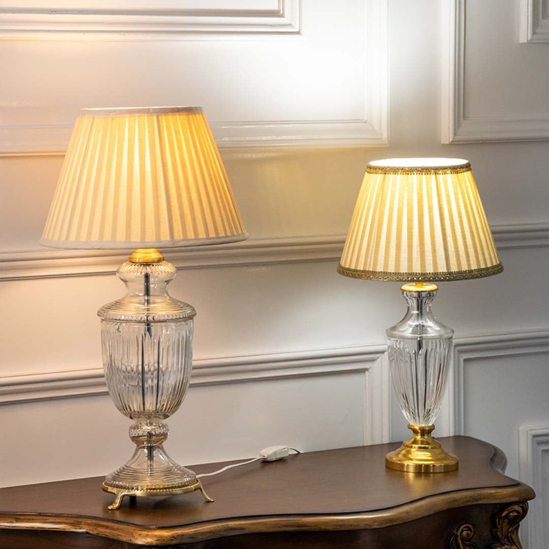 Crystal glass table lamps with pleated fabric shades emitting warm ambient light for elegant bedroom and living room decor.