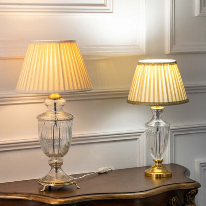 Crystal glass table lamps with pleated fabric shades emitting warm ambient light for elegant bedroom and living room decor.