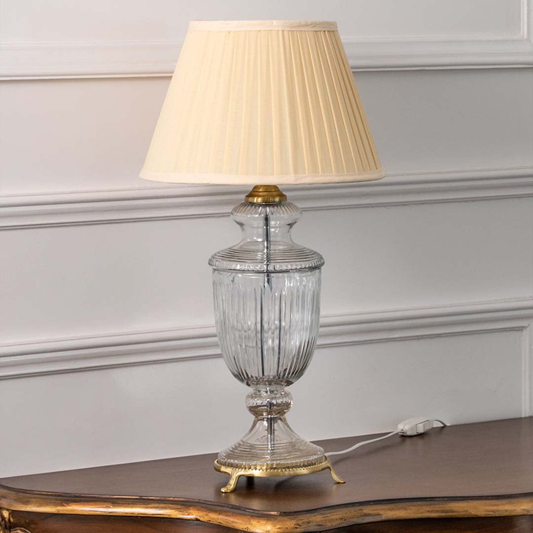 Crystal glass table lamp with white pleated shade and gold accents styled for sophisticated bedside table decor.