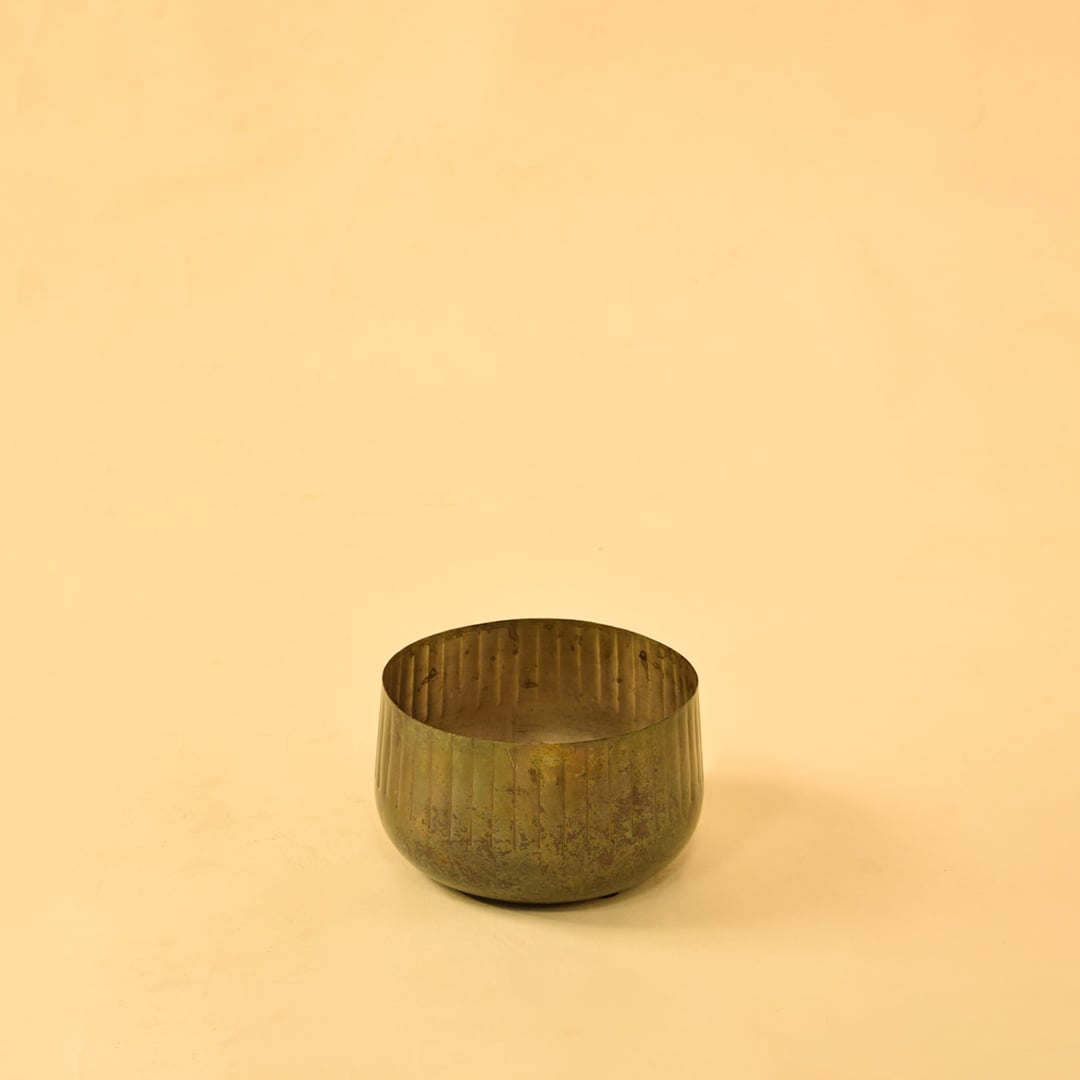 Ribbed metal bowl planter on a clean white background highlighting its simple natural rustic design.