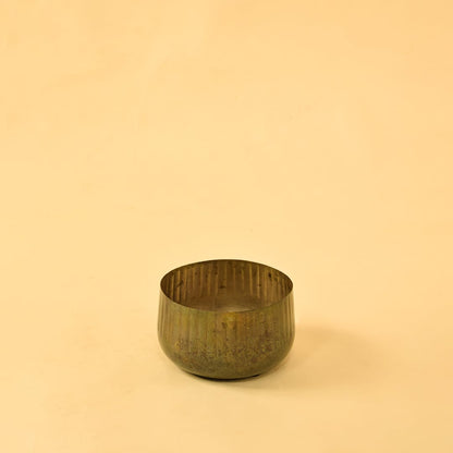 Ribbed metal bowl planter on a clean white background highlighting its simple natural rustic design.