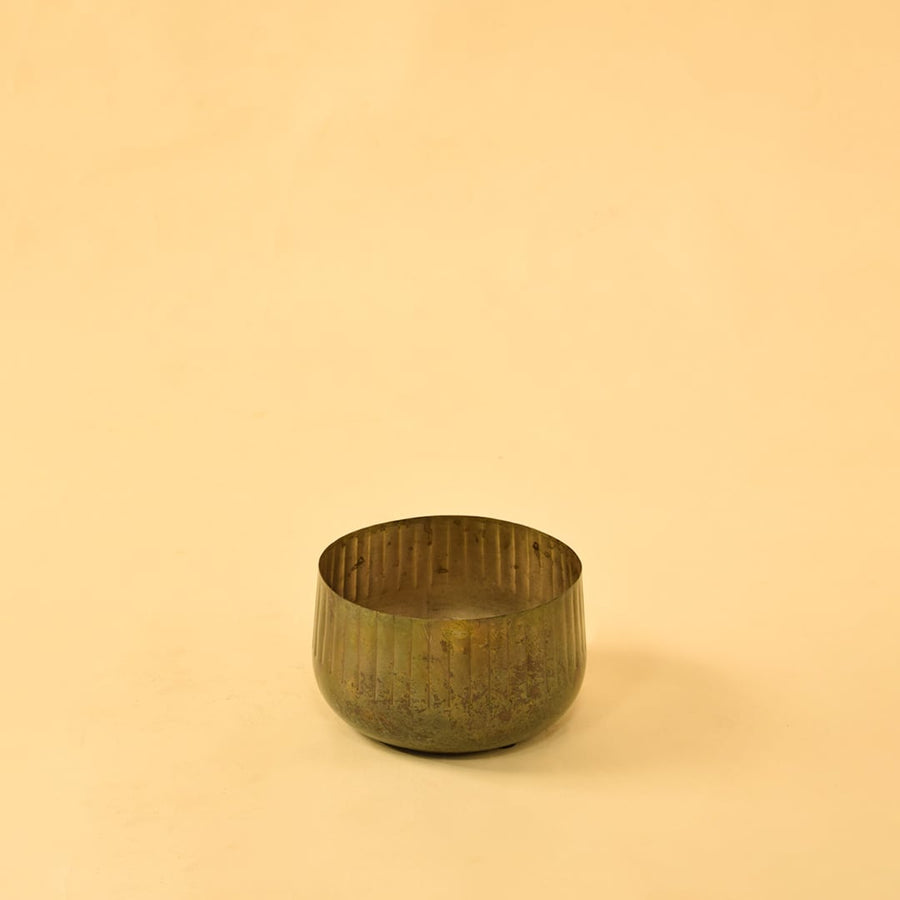 Ribbed metal bowl planter on a clean white background highlighting its simple natural rustic design.