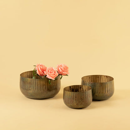 Bronze ribbed metal bowl planter placed with matching decor pieces creating a cohesive warm rustic styling look.