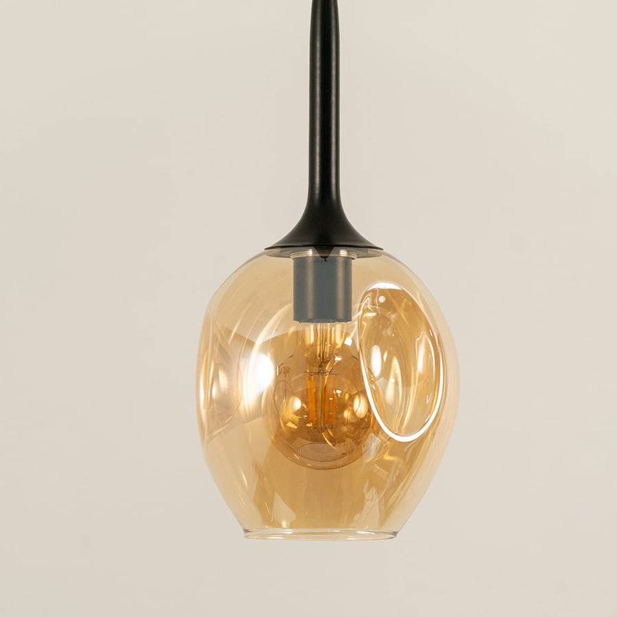 Closeup of amber glass pendant light with warm glow for modern interior lighting decor.