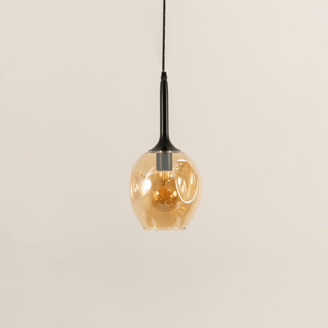 Amber glass pendant light turned off on white background for modern decor styling.