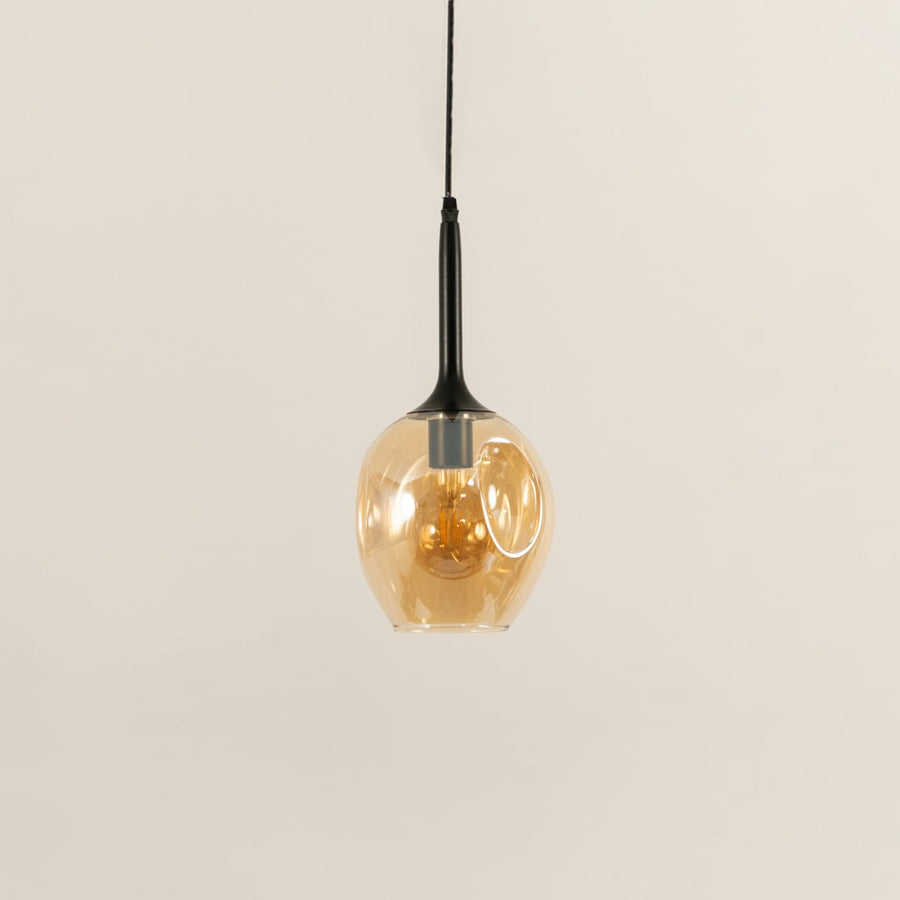 Amber glass pendant light turned off on white background for modern decor styling.