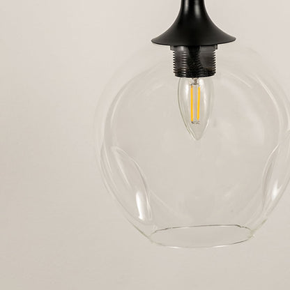 Detailed closeup of clear glass pendant light with visible filament bulb and black ceiling fixture.