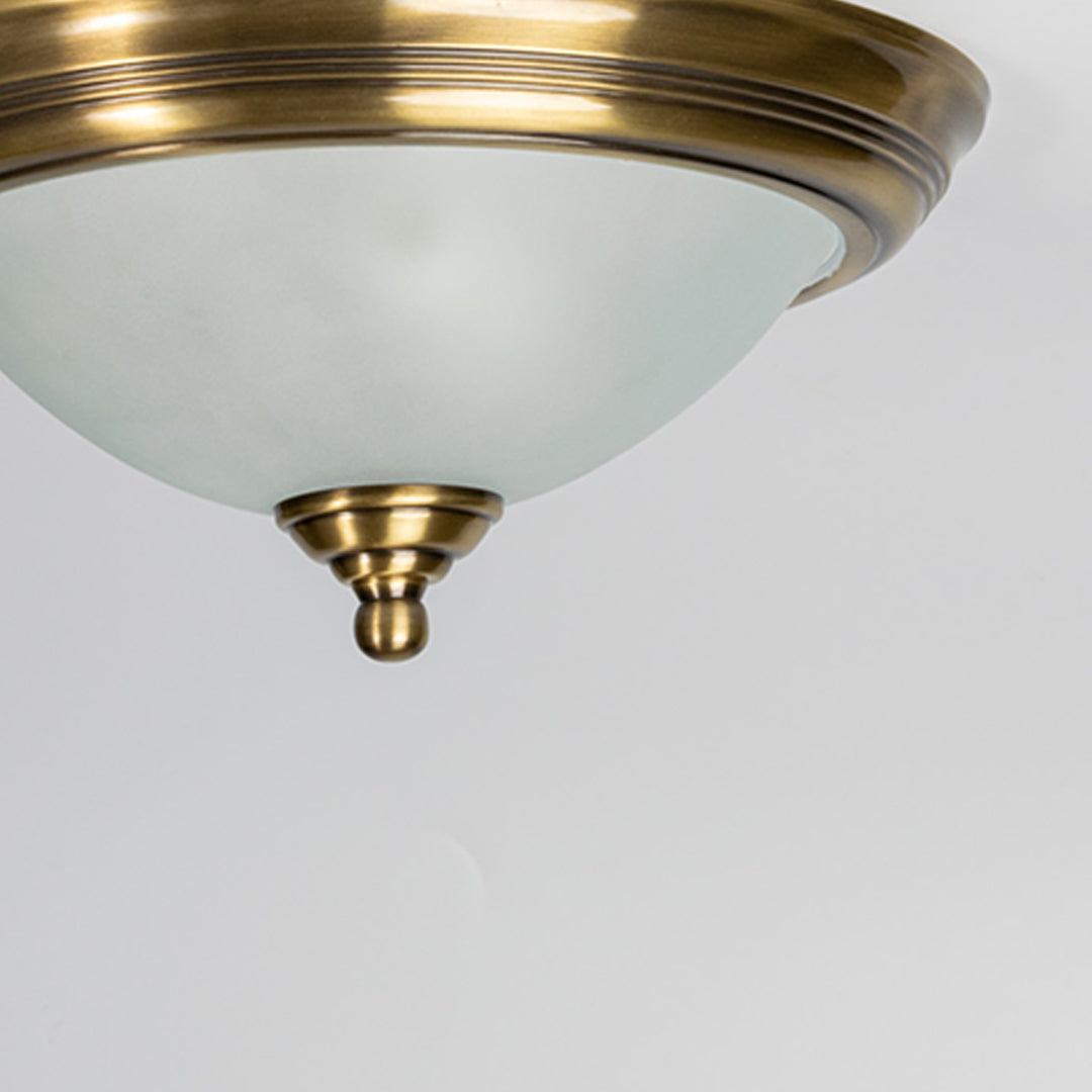 Closeup of frosted white glass and antique brass ceiling light for classic interior and premium decor styling spaces.