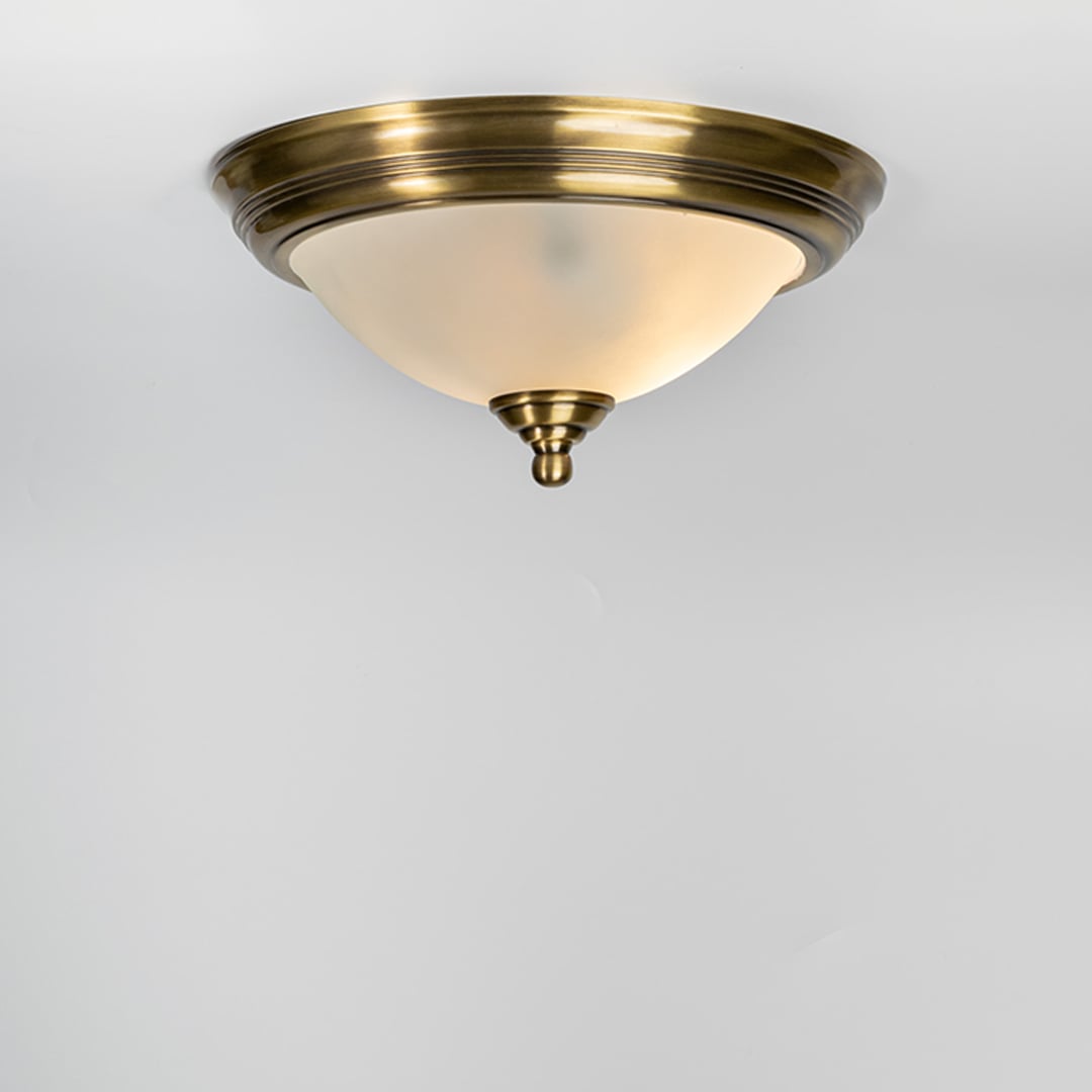 Modern antique brass flush mount ceiling light with frosted white glass shade for elegant hallway and luxury decor spaces.