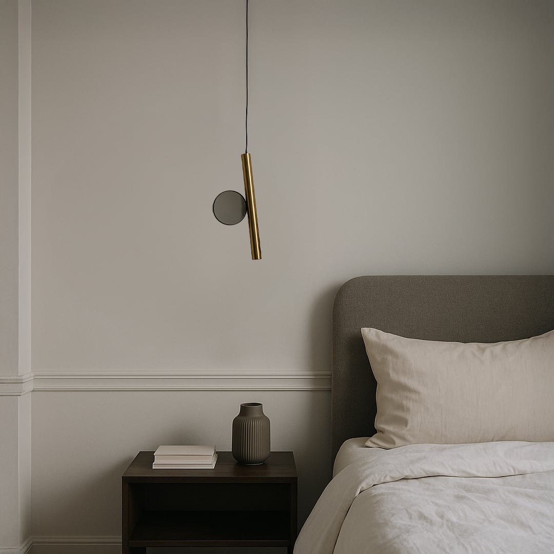 Modern gold tubular pendant light with circular glass accent glowing above bedside stylish ceiling lamp for luxury interiors.