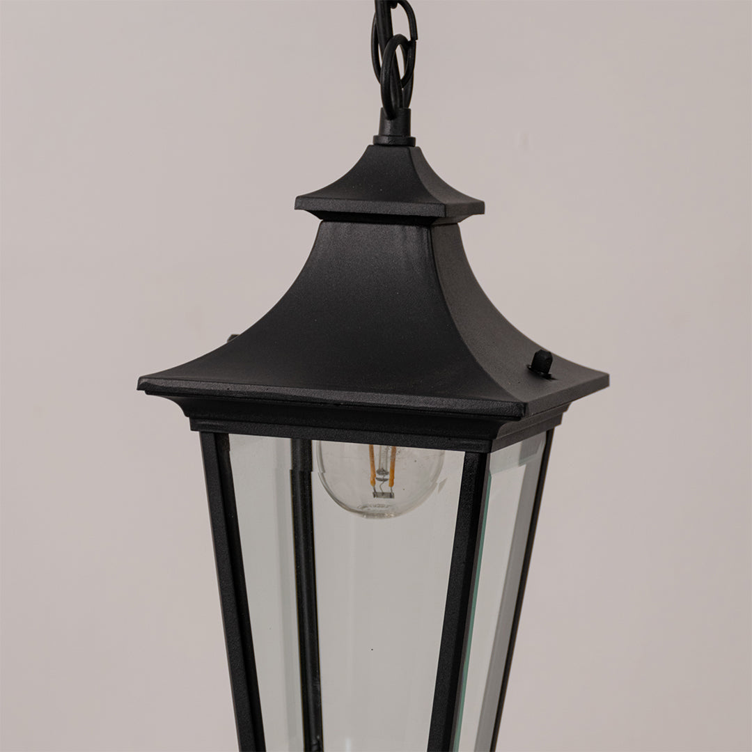 Closeup outdoor lantern in black metal finish with glass panels for garden or entrance decor lighting white background.