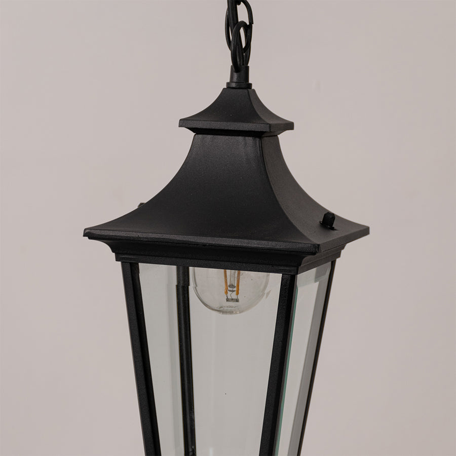 Closeup outdoor lantern in black metal finish with glass panels for garden or entrance decor lighting white background.