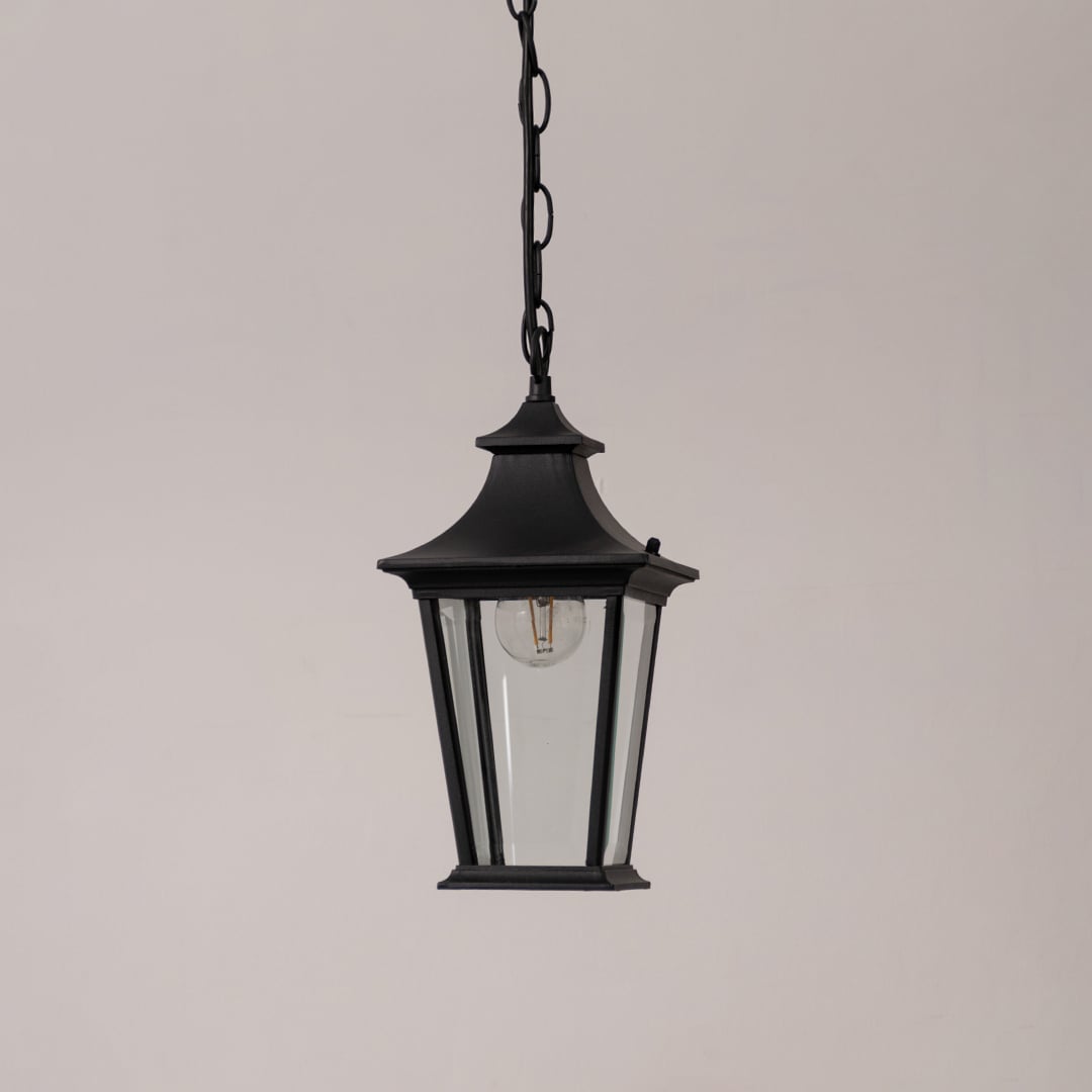 Black metal hanging lantern with clear glass panels displayed on a white background with the light switched off.