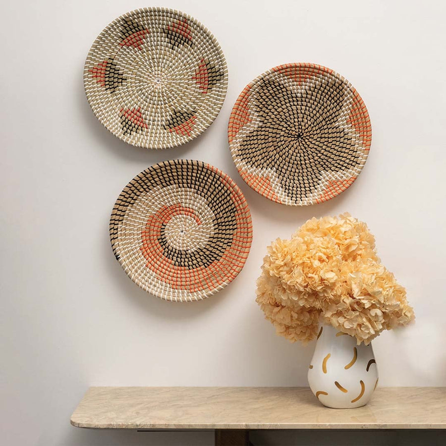 Decorative basket wall decor displayed on a neutral wall above a marble console with vase.
