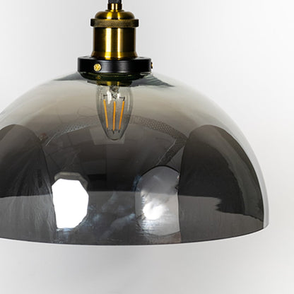 Closeup of smokey glass dome pendant light with brass and black fitting designed for elegant home interiors.