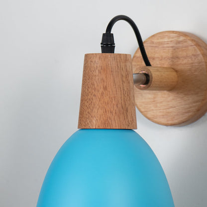 Closeup of wall sconce with matte teal blue metal shade natural wooden base and black cord showcasing elegant design.