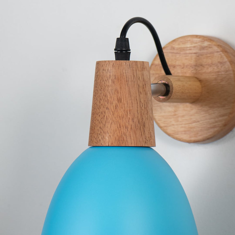 Closeup of wall sconce with matte teal blue metal shade natural wooden base and black cord showcasing elegant design.