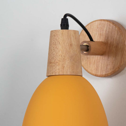 Closeup of modern wall lamp with matte yellow shade natural wooden base and black cord showcasing premium wall lighting design.