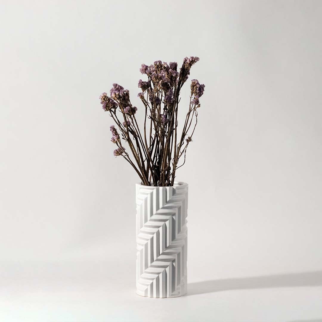 Soft purple dried flowers held in hand against a warm room setting adding rustic natural charm to modern home decor.