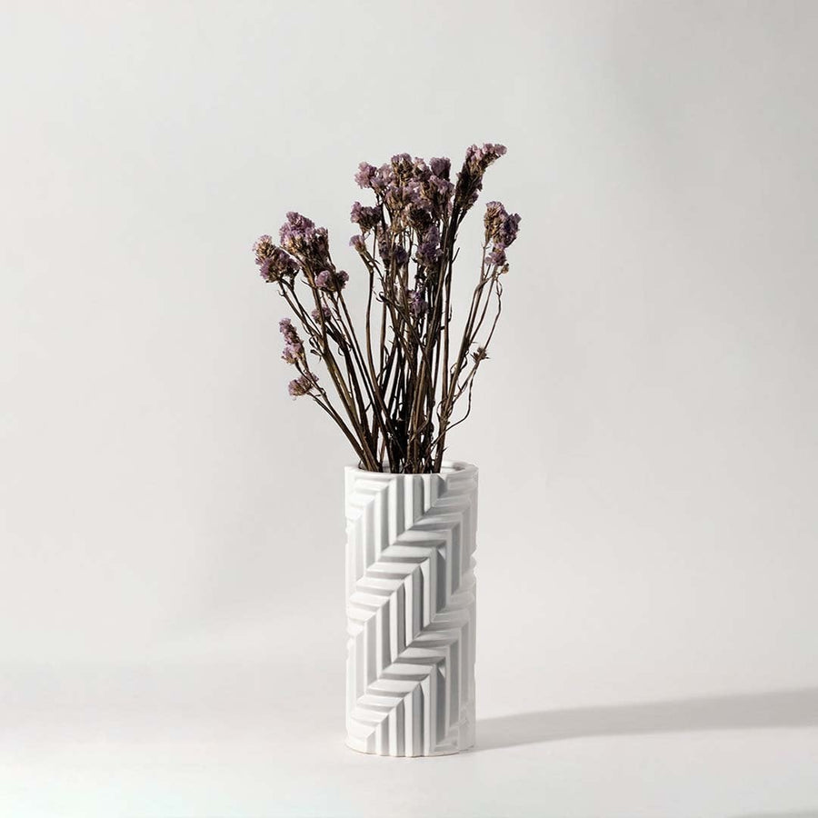 Soft purple dried flowers held in hand against a warm room setting adding rustic natural charm to modern home decor.