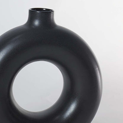 Closeup of matte black ceramic donut vase with smooth circular hollow design modern centerpiece for home decoration.