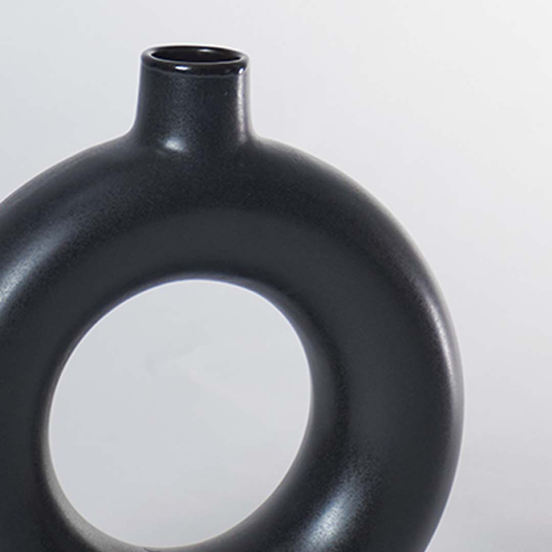 A closeup view of the black circular vase focusing on its smooth matte texture and perfectly rounded hollow center for a refined modern decor finish.