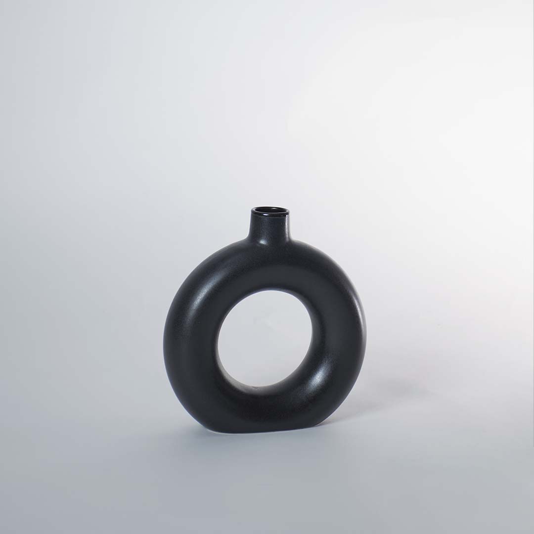 A minimalist black circular vase displayed on a white background showing its smooth matte finish and hollow center for a refined modern decorative look.