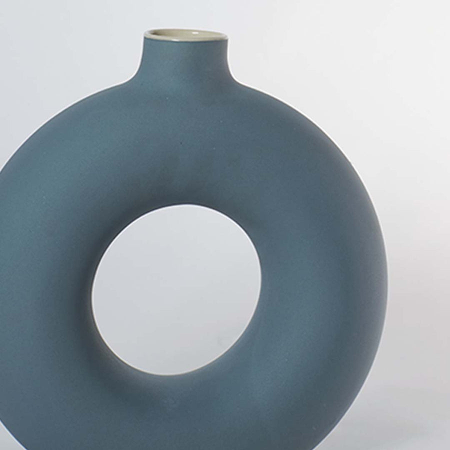 Closeup of matte green ceramic donut vase with smooth round hollow design modern centerpiece for living room decoration.