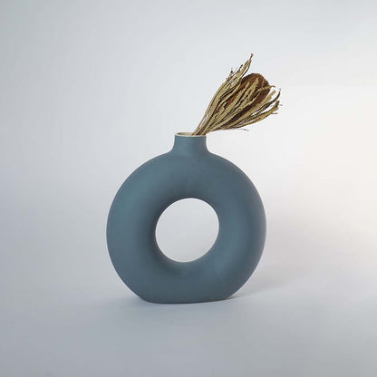 Modern green ceramic donut vase styled with dried stems placed on wooden console table for elegant home decor styling.