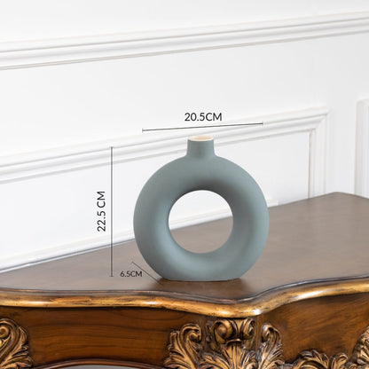 Minimalist green ceramic donut vase with smooth matte texture round hollow design ideal for tabletop and shelf decor.