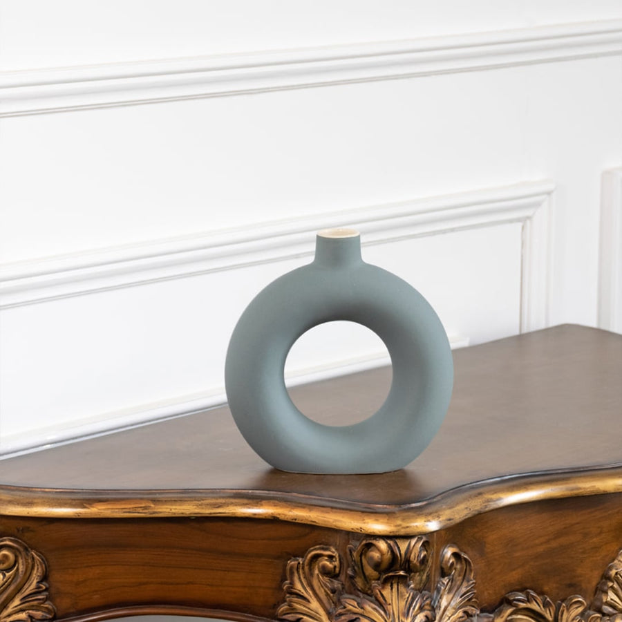 Minimalist green ceramic donut vase with smooth matte texture round hollow design ideal for tabletop and shelf decor.