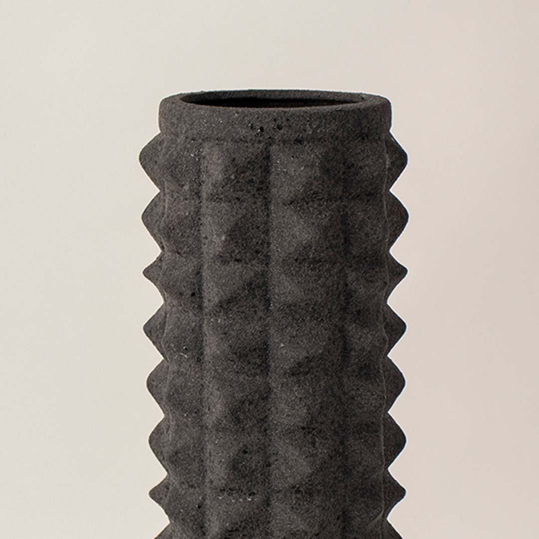 Closeup view of black ceramic vase highlighting its detailed geometric texture and matte finish ideal for table styling.